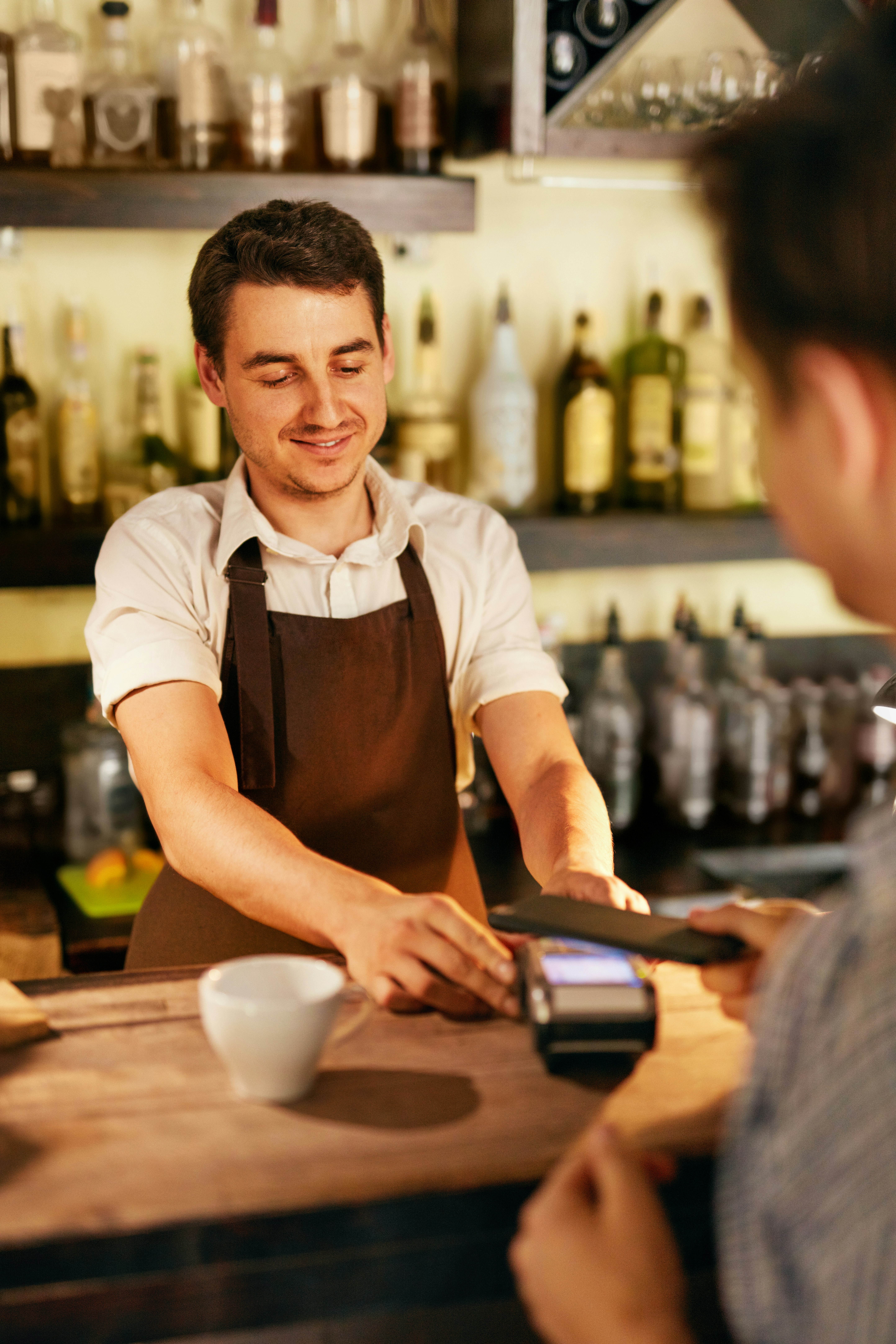 Merchant accepting mobile payment at bar counter — Total Pay Solutions