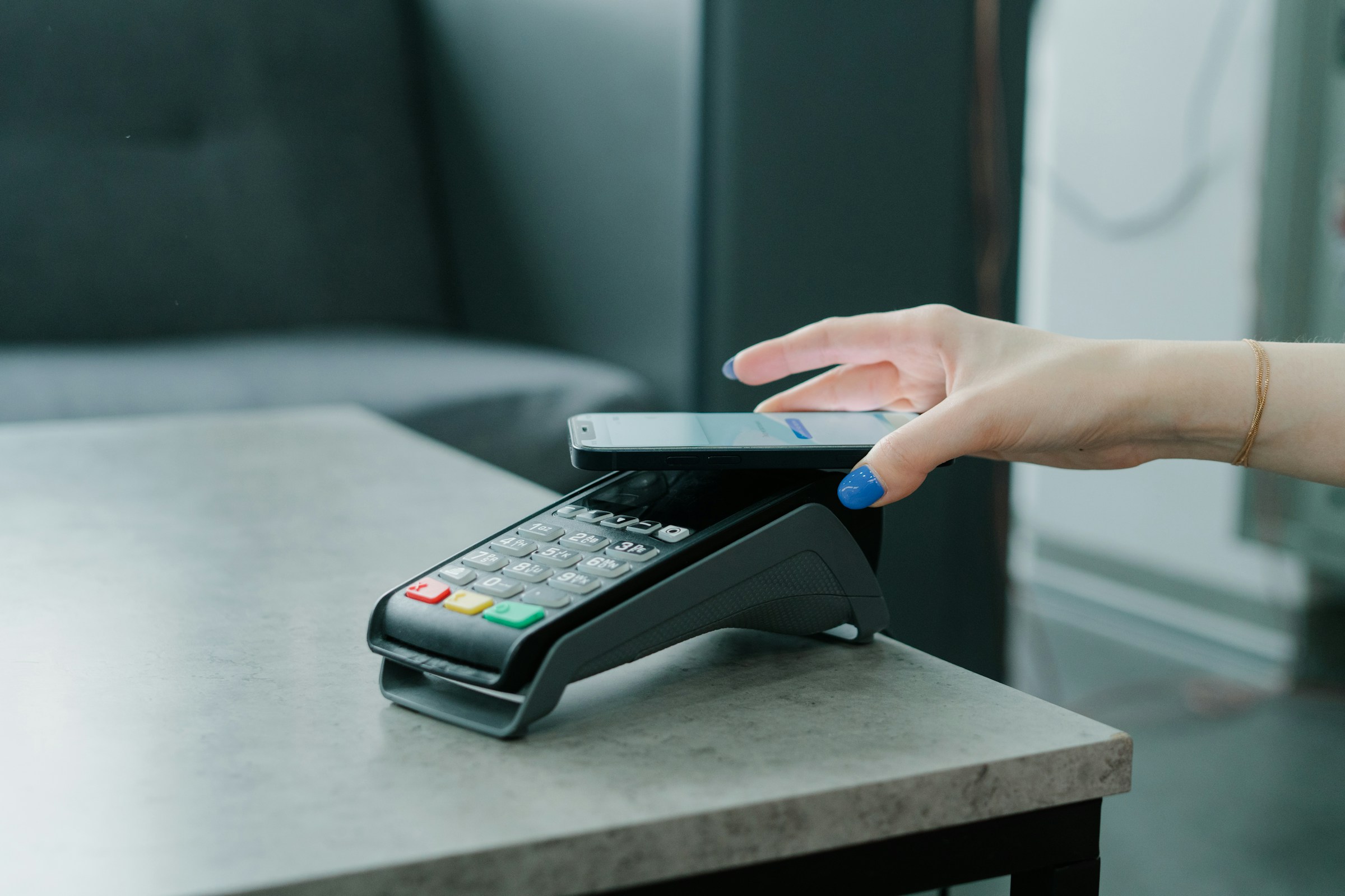 Hand holding phone over cash register for mobile payment